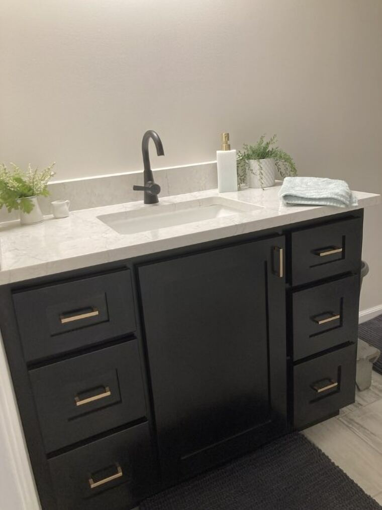 Black bathroom vanity with a marble-look quartz top