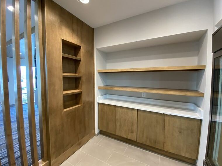 Built-in cabinetry with floating shelves beside a wood slat wall
