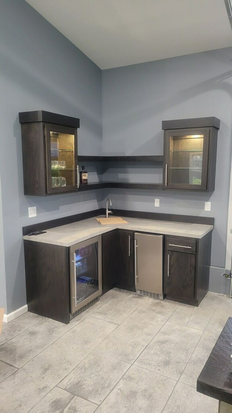 Dark-stained wet bar with lit glass-front cabinets and floating shelves