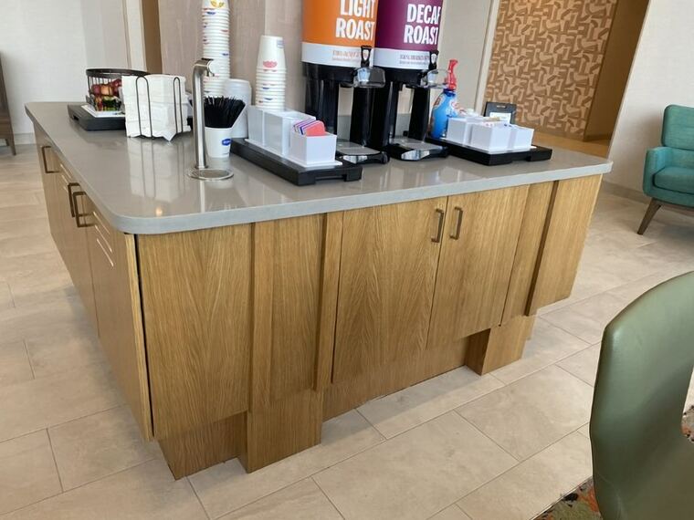 Hotel coffee service island with oak cabinetry and a quartz top