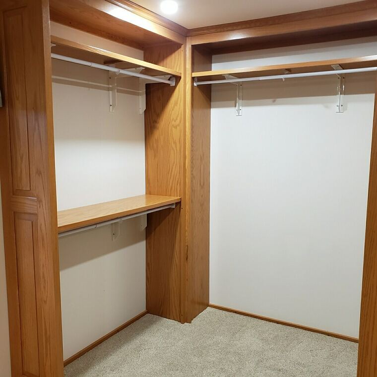 Oak closet built-ins with hanging rods and a shelf counter
