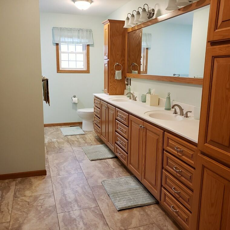 Oak double vanity with a linen tower and framed mirror