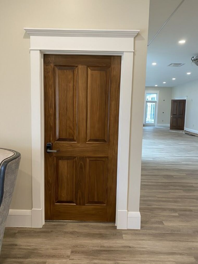 Stained panel door set in painted casing with a built-up header