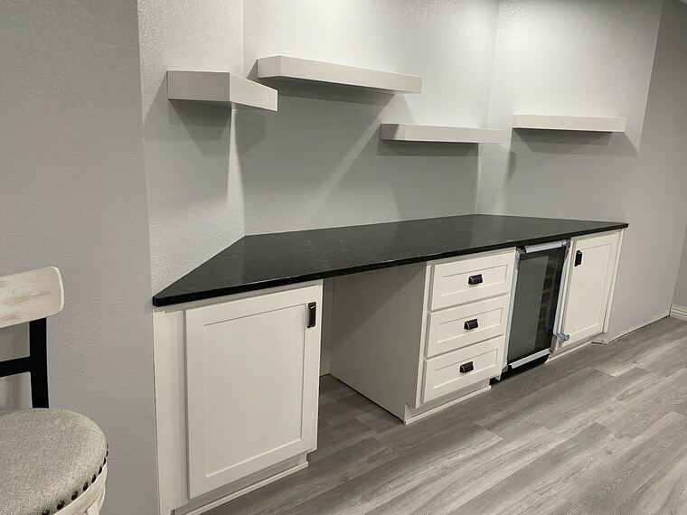 White cabinet bar with a black granite top and floating shelves