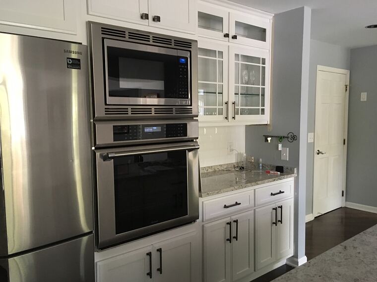 White kitchen with glass-front upper cabinets and a granite counter