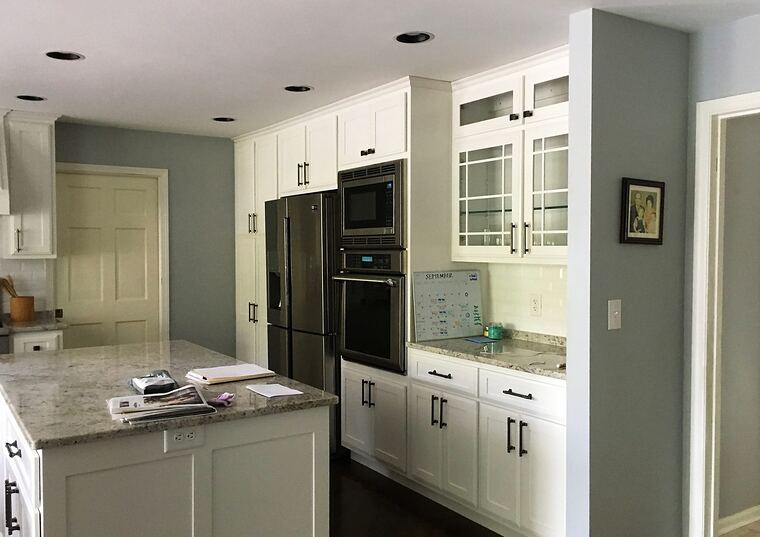 White kitchen with a granite-topped island and tall cabinetry