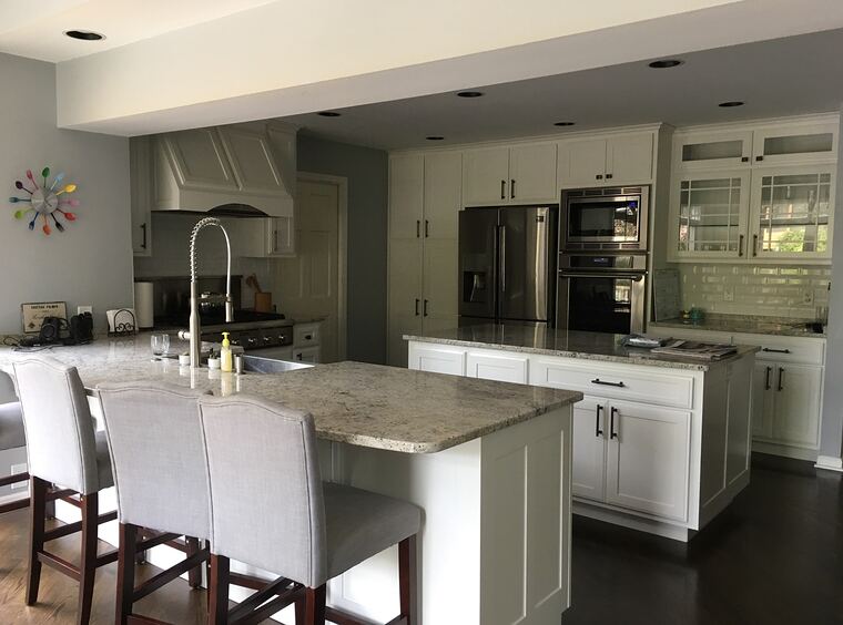 White kitchen with island seating and a painted wood hood